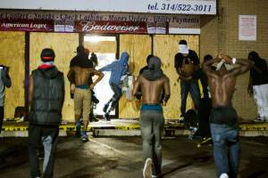 Masked individuals carry items out of a liquor store, during on-going demonstrations to protest against the shooting of Michael Brown, in Ferguson